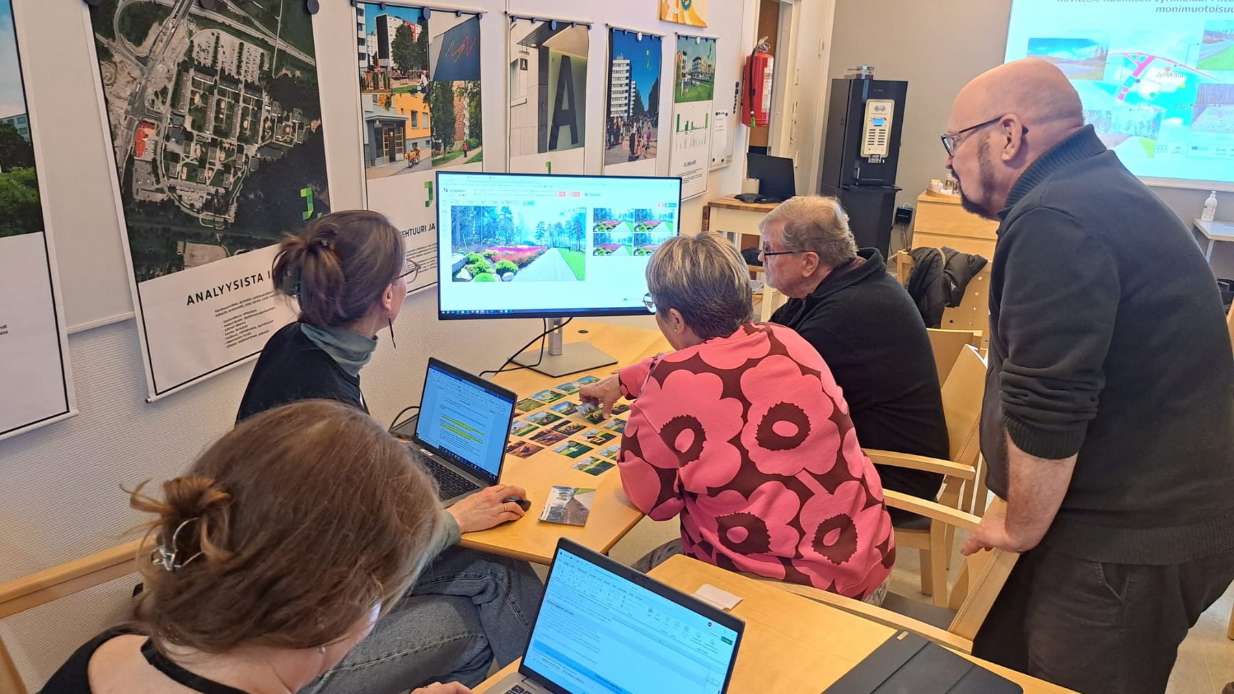 Residents and practitioners at laptops with element cards, a park scenario on the screen.
