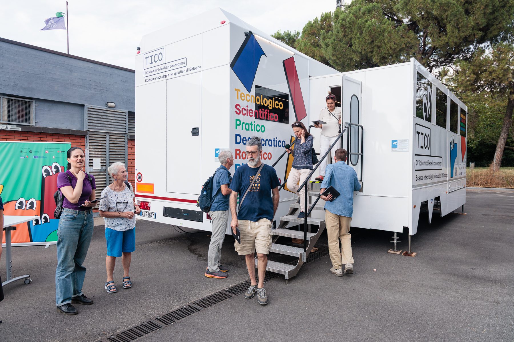 The TICO workshop truck parked in a Bologna neighbourhood, people climbing its steps.