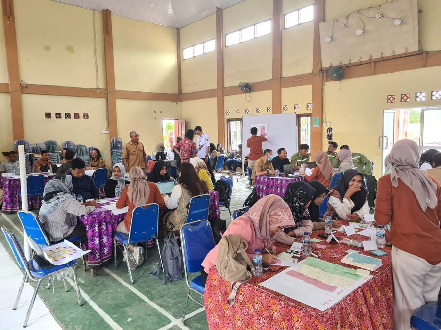 Dozens of people working in a classroom around tables